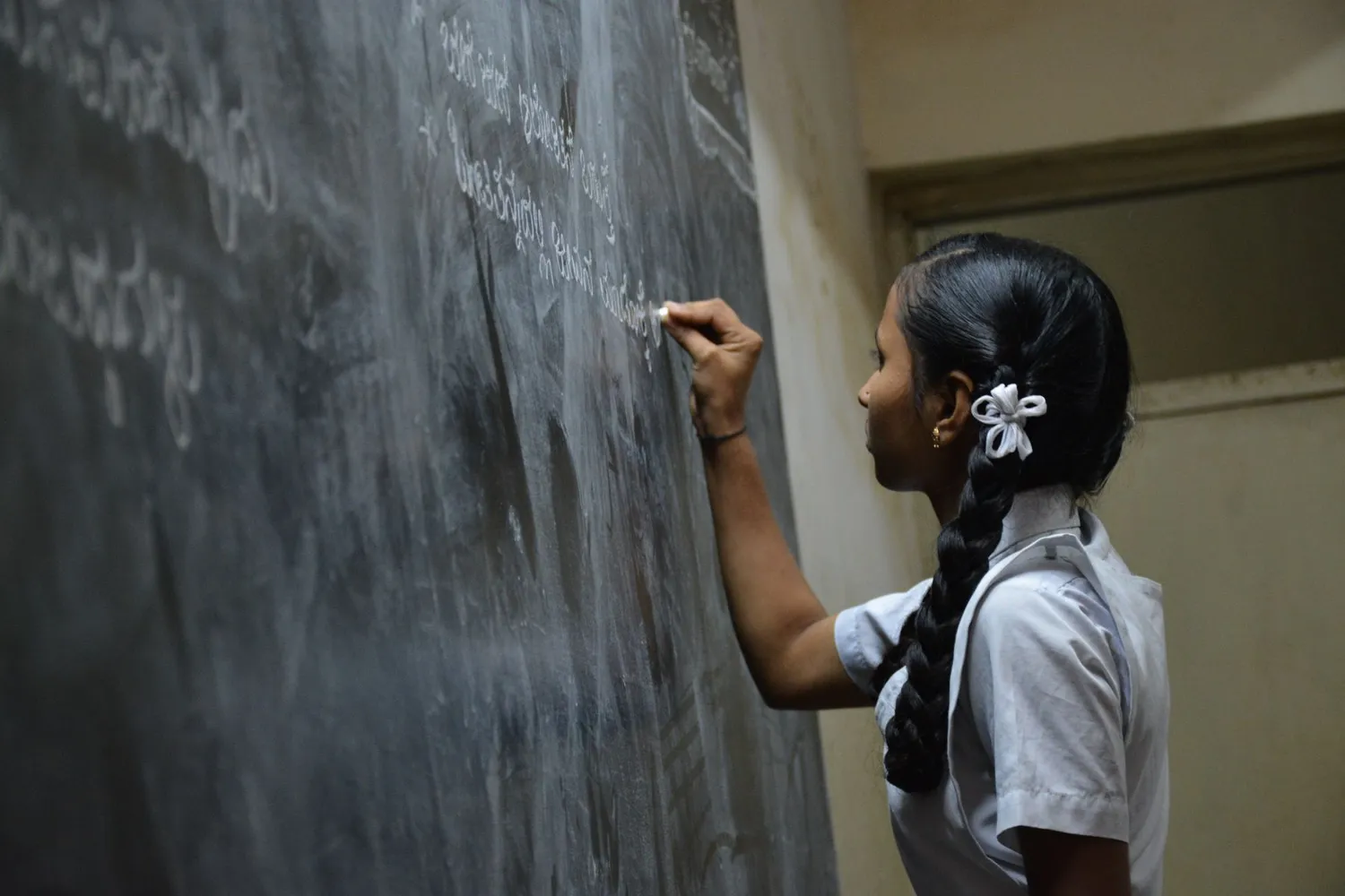 Una alumna escribe en el pizarrón de su aula.
