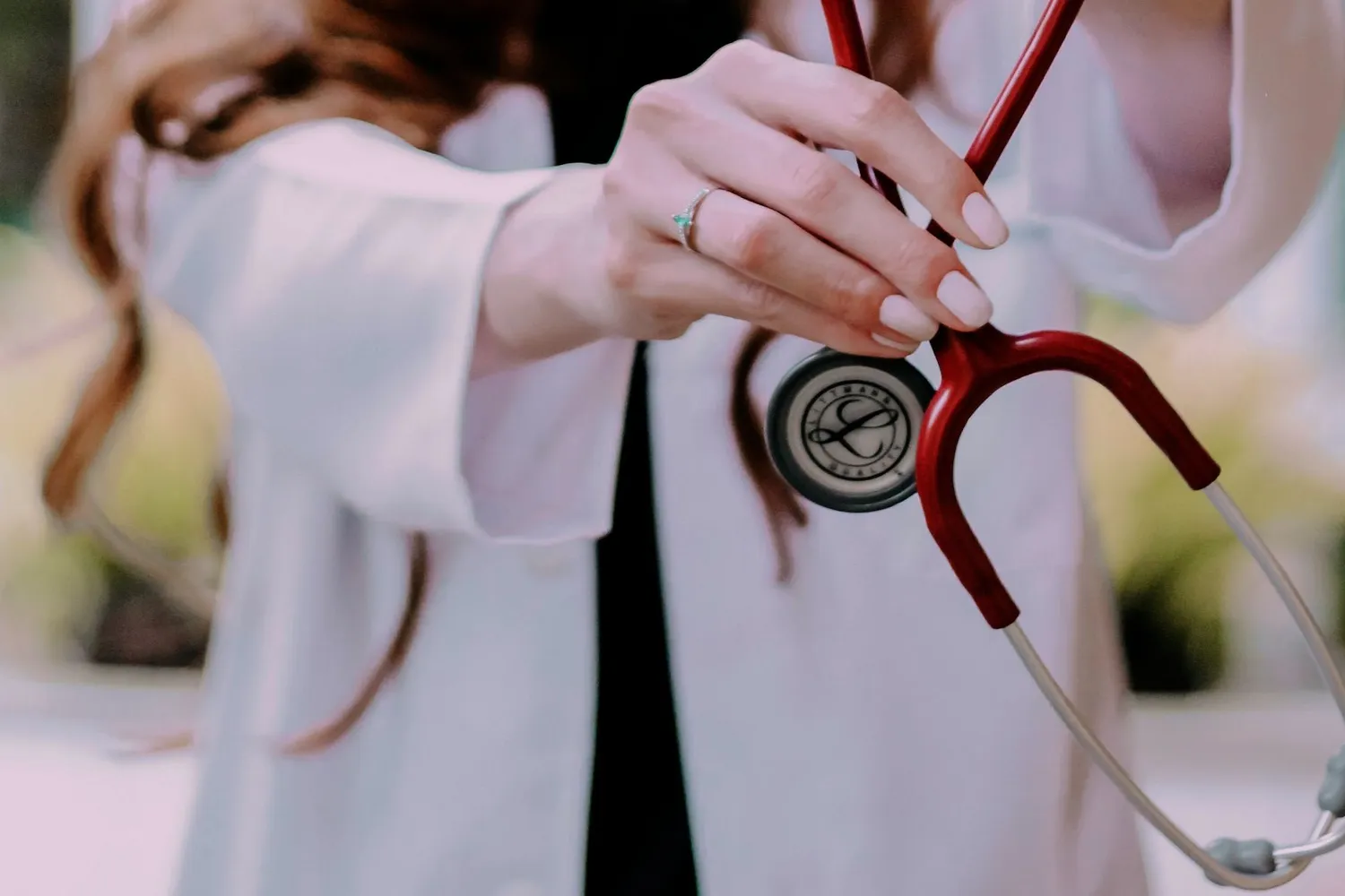 Una médica con guardapolvo blanco sostiene un estetoscopio.